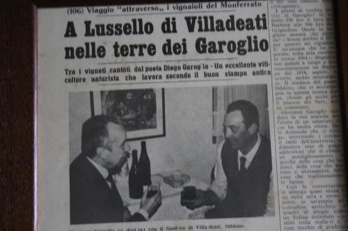 a newspaper with two men sitting at a table with a bottle of wine at Azienda Agricola Garoglio Davide in Alfiano Natta