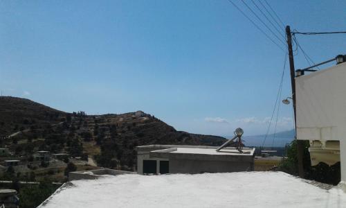 a building with snow on the roof with a mountain at Studio Galatia, in the heart of Kamilari in Kamilari
