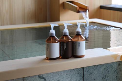 three bottles of liquid sitting on a ledge next to a swimming pool at Sekizenkan Kashotei Sanso in Nakanojo