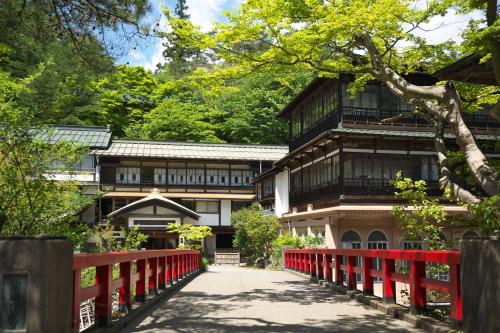 a red bridge in front of a building with a red fence at Sekizenkan Kashotei Sanso in Nakanojo