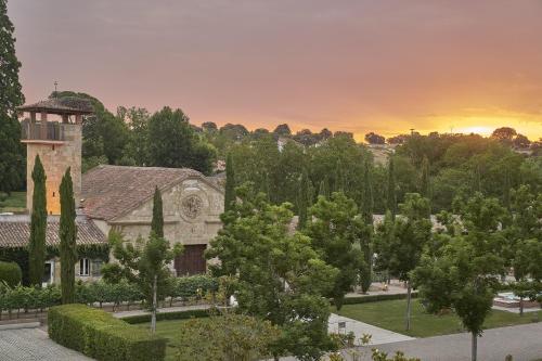 a building with a tower in a park with trees at Hacienda Zorita Wine Hotel & Spa in Valverdón