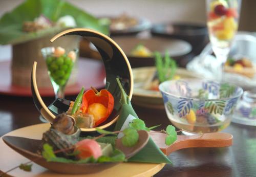 a bowl of fruit on a table with plates of food at Sekizenkan Kashotei Sanso in Nakanojo