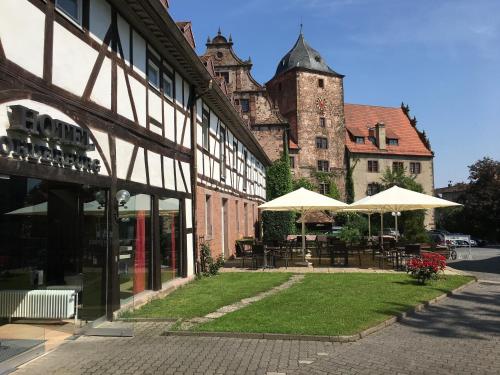 a building with tables and umbrellas in front of it at Hotel Vorderburg in Schlitz