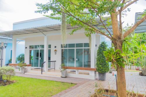 a home with a porch and a tree at The Cube Resort in Chanthaburi
