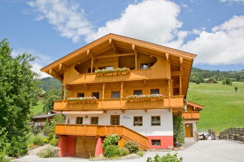 a wooden house with a balcony on a hill at Aparthotel Hummerau in Alpbach