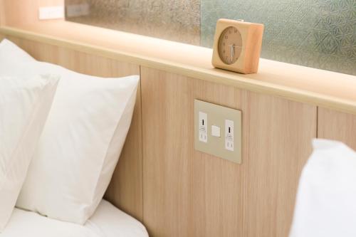 a clock on a wall next to a bed with pillows at Hakone Ashinoko Hanaori in Hakone