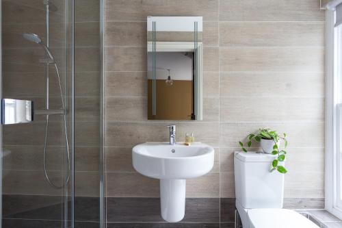 W łazience znajduje się umywalka, toaleta i lustro. w obiekcie Peckham Rooms Hotel w Londynie