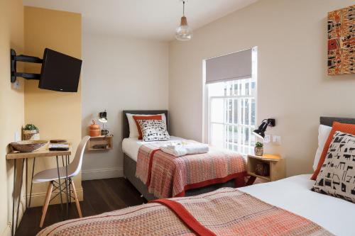 1 dormitorio con 2 camas, escritorio y ventana en Peckham Rooms Hotel, en Londres