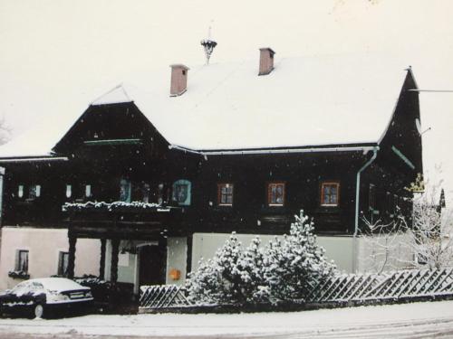 a house covered in snow with a car in front at Moarhof in Aich