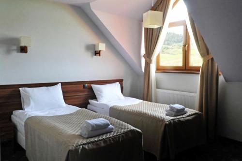 two beds in a room with a window at Zajazd Bieszczadzka Ostoja in Ustrzyki Dolne