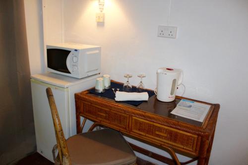 a room with a desk with a microwave and a tv at Chantauvent Guest House in Blue Bay