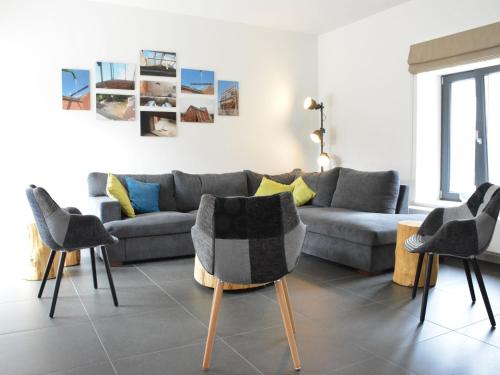 sala de estar con sofá gris y sillas en Modern Holiday Home in Fernelmont with Garden, en Forville