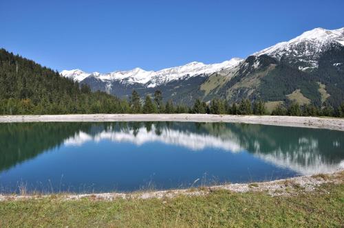 a small lake with snow capped mountains in the background at Haus Bergfrieden in Lermoos