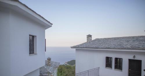 a view of the ocean from between two white buildings at Pilio Sea Horizon Hotel in Tsagarada
