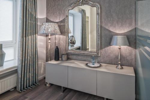 a bathroom with a vanity with a mirror and a lamp at Hotel Prinz Anton in Düsseldorf