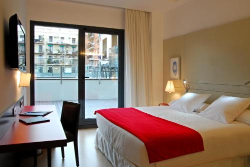 a hotel room with a bed and a desk and a window at Grupotel Gran Via 678 in Barcelona