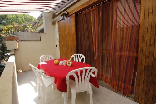 a table with white chairs and a red table cloth at I Ginepri in Sorso