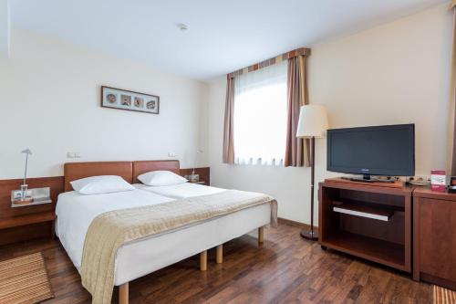 a bedroom with a bed and a flat screen tv at Qubus Hotel Gliwice in Gliwice