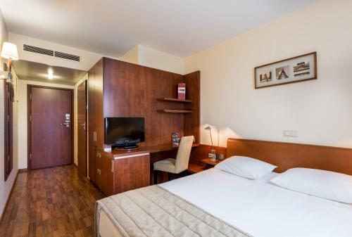 una camera d'albergo con letto e scrivania con TV di Qubus Hotel Gliwice a Gliwice