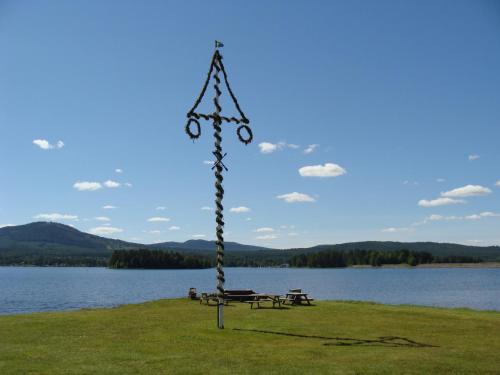 a pole with a bench and a picnic table next to a lake at Tomtelandstugan in Mora