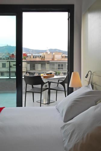 a bedroom with a bed and a table and a large window at Grupotel Gran Via 678 in Barcelona