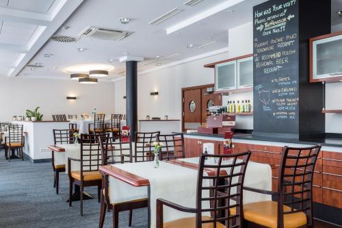 a dining room with tables and chairs and a chalkboard at Qubus Hotel Gliwice in Gliwice