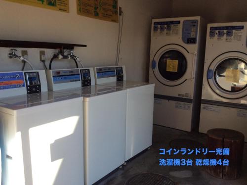 a laundry room with three washing machines and a counter at Business Hotel Shizusato Ryokan in Ogaki