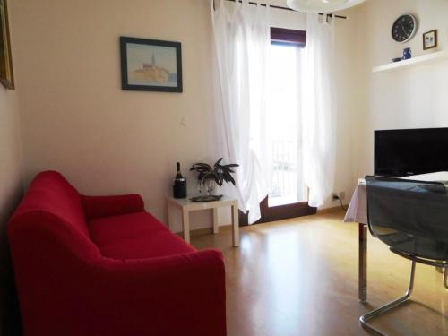 a living room with a red couch and a tv at Casa Pastoricchio in Grado