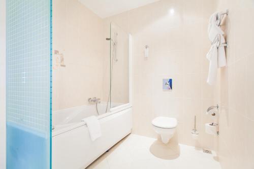 y baño blanco con aseo y ducha. en Qubus Hotel Gliwice, en Gliwice