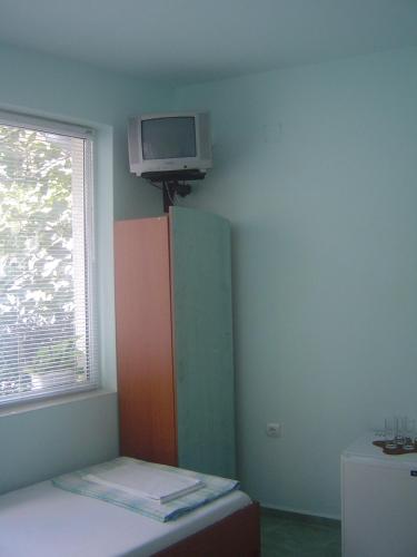 a room with a cabinet and a tv on the wall at Guest House Dimovi in Sozopol