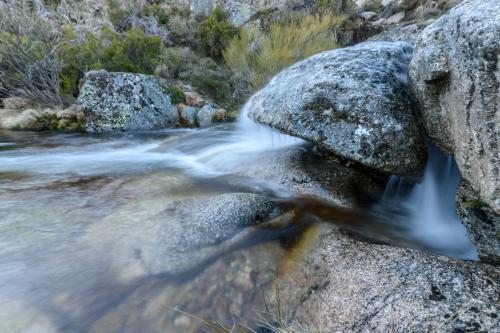 a river with rocks and water rushing through it at Luna Chalets da Montanha - Serra da Estrela in Covilhã