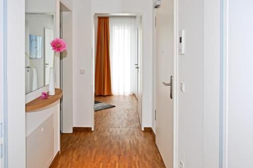 a hallway with white walls and wood flooring and a room with a window at DünenResort in Binz, strandnahe und moderne FeWos mit Balkon, teilweise mit Meerblick, in Binz