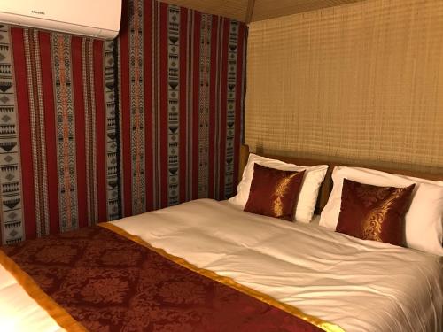a bedroom with a bed with white sheets and pillows at Bedouin Oasis Desert Camp- Ras Al Khaimah in Ras al Khaimah