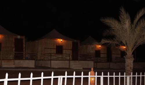 a person standing in front of a fence at night at Bedouin Oasis Desert Camp- Ras Al Khaimah in Ras al Khaimah