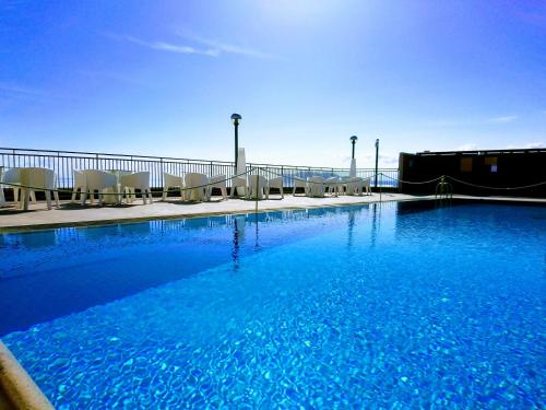 ein großer Pool mit Stühlen und blauem Wasser in der Unterkunft San Paolo Palace Hotel in Palermo