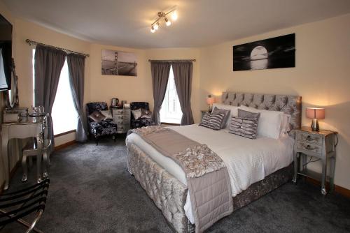 a bedroom with a bed and a chair and windows at Star Inn Rooms in Ardersier