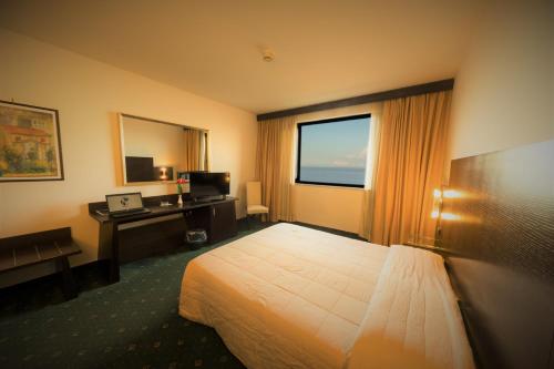 パレルモにあるサンパウロ パレス ホテルのベッド、デスク、窓が備わるホテルルームです。