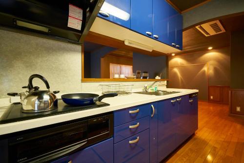 a kitchen with blue cabinets and a pot on the stove at Guesthouse Nijo Fukuro-Tei in Kyoto