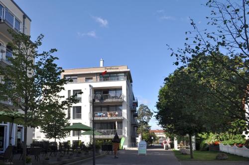 a white building with tables and chairs in front of it at DünenResort in Binz, strandnahe und moderne FeWos mit Balkon, teilweise mit Meerblick, in Binz