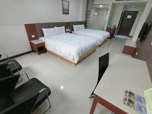 a hotel room with two beds and a desk at 雲林斗六福爾摩莎大飯店 in Douliu