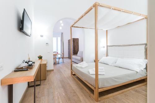 B&B Il Palazzotto Luxury Suites في ليتشي: غرفة نوم مع سرير المظلة ومكتب