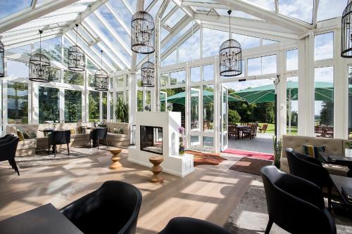 a conservatory with chairs and tables and a fireplace at SCHLOSS Fleesensee in Göhren-Lebbin