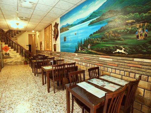 a restaurant with wooden tables and a large painting on the wall at Sun Moon Lake Fisherman Homestay in Yuchi