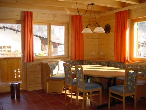 a dining room with a table and chairs and windows at Chalet Montafon in Vandans