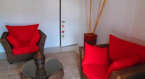 a living room with two chairs and a table with red pillows at Le Castel Blanc Hotel Boutique in San Andrés