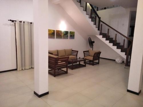 a living room with chairs and a staircase at Villa Red Lobster in Hikkaduwa