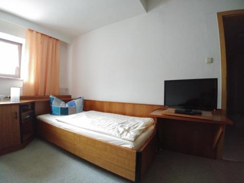 a bedroom with a bed and a flat screen tv at Gasthof & Hotel Zur Linde in Thum