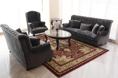 a living room with a couch and a table and two chairs at Namira Syariah Hotel Surabaya in Surabaya