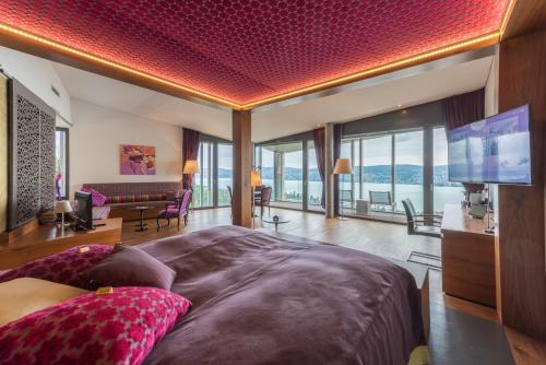 リュシュリコンにあるHotel Belvoir Lake View & Spaの大きなベッドと薄型テレビのある寝室