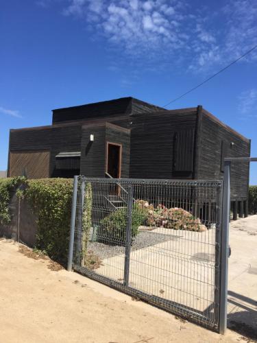 Ein schwarzes Haus mit einem Zaun davor. in der Unterkunft Casa Playa in Navidad